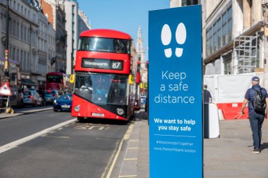 Londra, İngiltere - 1 Haziran 2021: Londra 'da Strand yolunda bir otobüsün arka planında güvenli bir mesafede durmasını isteyen bir tabela