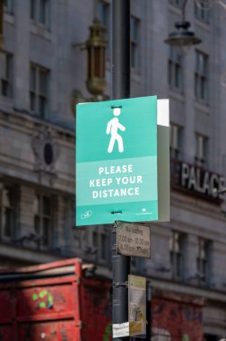 Londra, İngiltere - 1 Haziran 2021: İnsanlardan arka planda binalar olan bir sokakta mesafelerini korumalarını isteyen bir tabela.