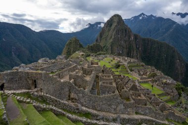 Machu Picchu 'nun Peru' daki panoramik manzarası harabe. Arkasında yeşil bitki örtüsüyle dolu büyük ve güzel dağları takdir edebiliriz. Arkeolojik alan, Unesco Dünya Mirası