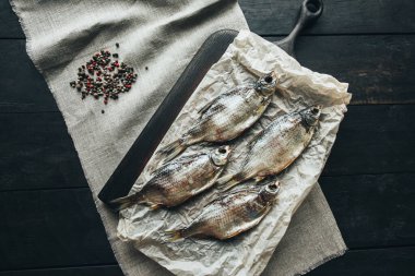 Lezzetli taze, kurutulmuş vahşi deniz nehri kırmızı ve beyaz balıklar ahşap bir kahverengi tahta üzerinde kağıt üzerinde keten kumaş, bez, börgü, koç, uskumru, ringa balığı, baharatlar ve ahşap bir masa üzerinde güzel bir renk kombinasyonu.