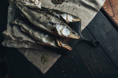 Lezzetli taze, kurutulmuş vahşi deniz nehri kırmızı ve beyaz balıklar ahşap bir kahverengi tahta üzerinde kağıt üzerinde keten kumaş, bez, börgü, koç, uskumru, ringa balığı, baharatlar ve ahşap bir masa üzerinde güzel bir renk kombinasyonu.