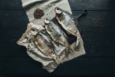 Lezzetli taze, kurutulmuş vahşi deniz nehri kırmızı ve beyaz balıklar ahşap bir kahverengi tahta üzerinde kağıt üzerinde keten kumaş, bez, börgü, koç, uskumru, ringa balığı, baharatlar ve ahşap bir masa üzerinde güzel bir renk kombinasyonu.