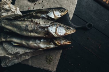 Lezzetli taze, kurutulmuş vahşi deniz nehri kırmızı ve beyaz balıklar ahşap bir kahverengi tahta üzerinde kağıt üzerinde keten kumaş, bez, börgü, koç, uskumru, ringa balığı, baharatlar ve ahşap bir masa üzerinde güzel bir renk kombinasyonu.