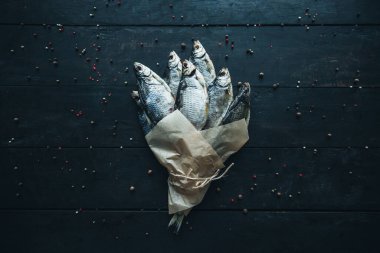 Parşömen kağıdına sarılı lezzetli gümüş koç balığı. Koyu ahşap masa üzerinde farklı baharat buketleriyle sarılı bir halatla yemek pişirmek için.