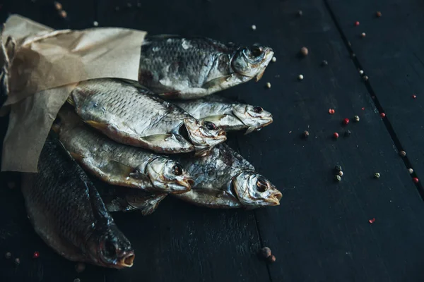 delicious dried silver ram fish wrapped in paper in parchment paper for cooking wrapped with a rope on the dark wooden table with different kinds of spices bouquet of fish