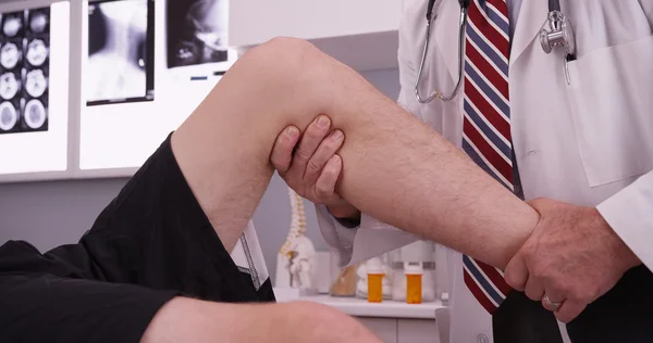 Senior kaukaski lekarz badając kontuzji kolana — Zdjęcie stockowe
