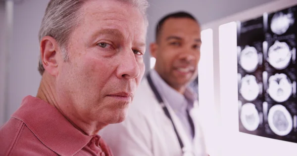 Paciente masculino mayor mirando a la cámara con práctica médica joven — Foto de Stock