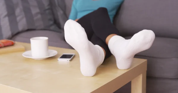 Mujer descansando sus pies en la mesa de café — Foto de Stock