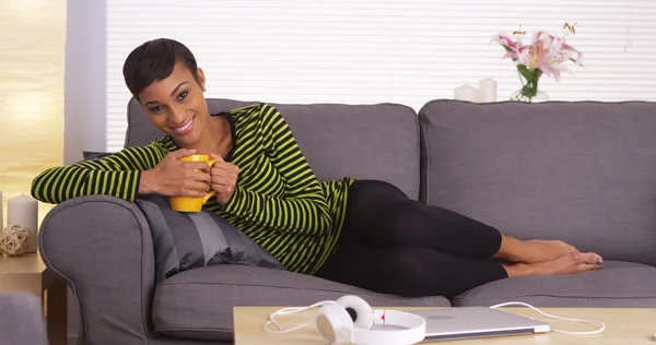 Afrikanerin hält Becher auf Couch — Stockfoto
