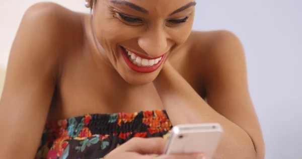 African woman happily using smartphone — Stock Photo, Image