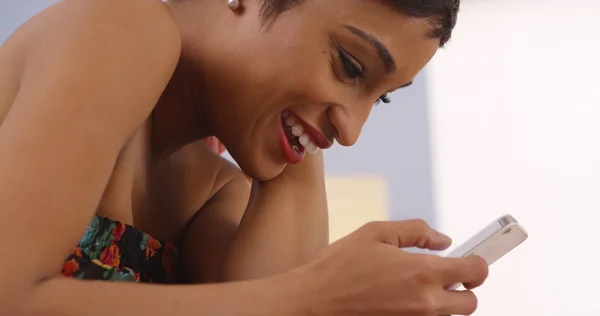 Zwarte vrouw die lacht tijdens het gebruik van smartphone — Stockfoto
