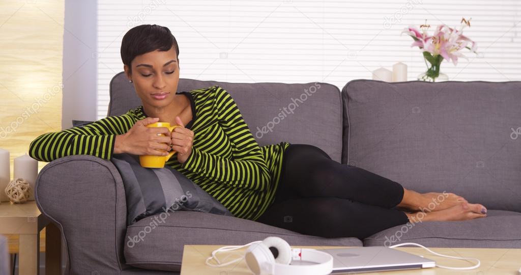 Black woman relaxing on couch with mug