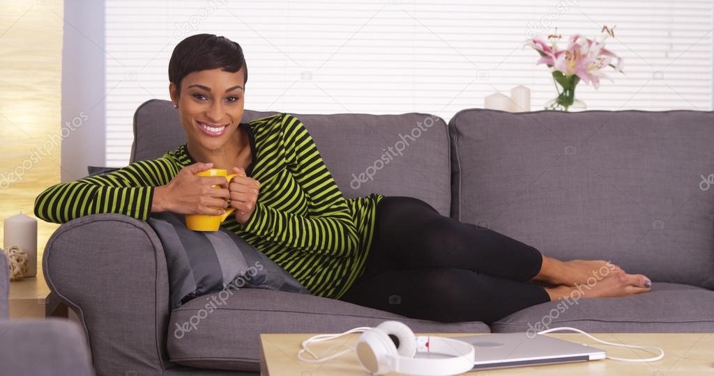 African woman holding mug on couch