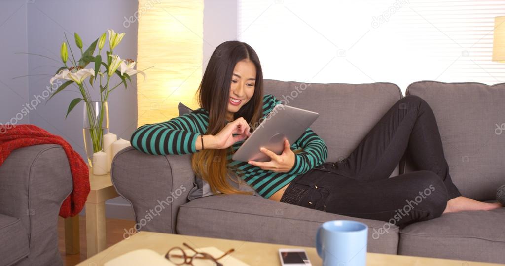 Cute Japanese woman using tablet on couch