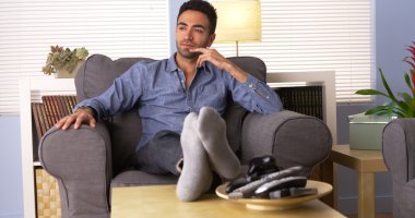 Handsome Latino sitting at home thinking clipart