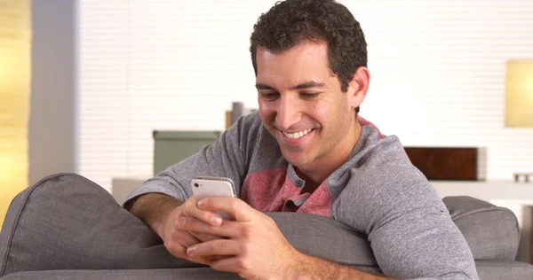 Человек счастливо пишет смс на смартфоне — стоковое фото