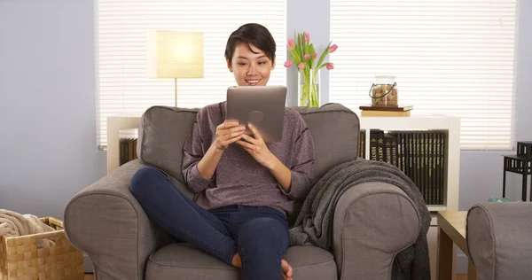 Cute Chinese woman using tablet on couch — Stock Photo, Image