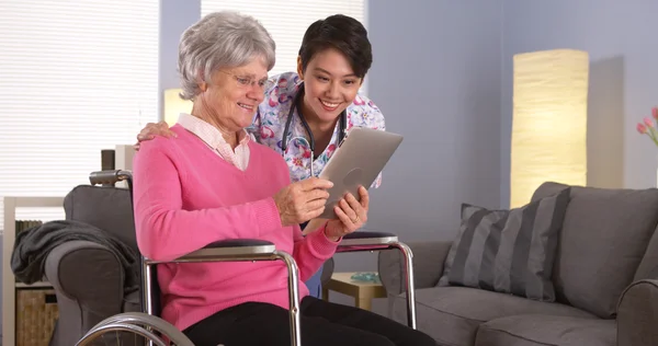Elderly patient and Asian nurse talking with tablet — Stock Photo, Image