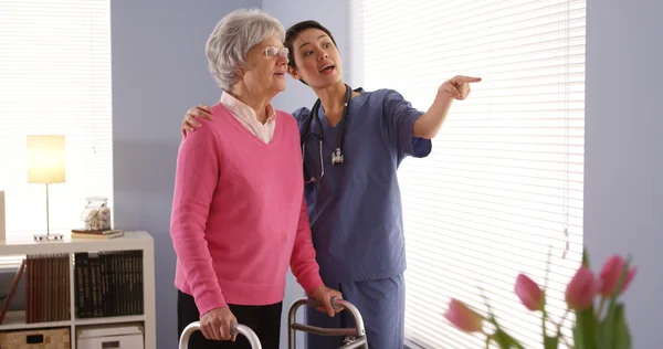 Kinesiska sjuksköterska och äldre kvinna patienten tittar ut fönstret — Stockfoto