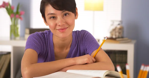 Asiatin lächelt am Schreibtisch mit Büchern — Stockfoto