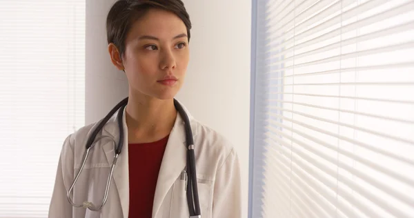 Selbstbewusste chinesische Ärztin steht am Fenster — Stockfoto