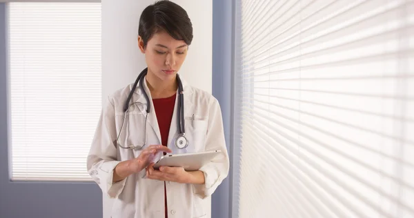 Aziatische vrouw arts Tablet PC via venster — Stockfoto