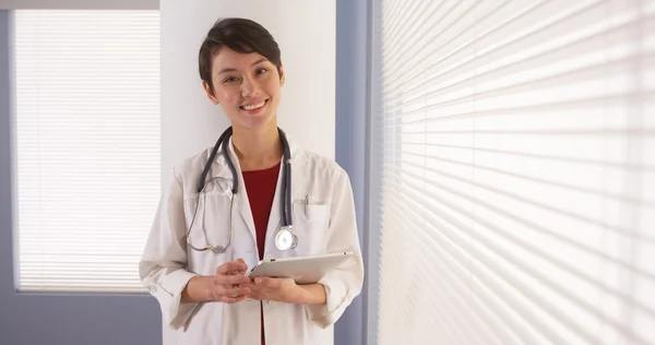 タブレットで窓のそばに立って成功した中国女性医師 — ストック写真