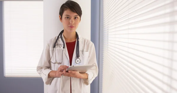 Asian woman doctor using tablet by window — Stock Photo, Image