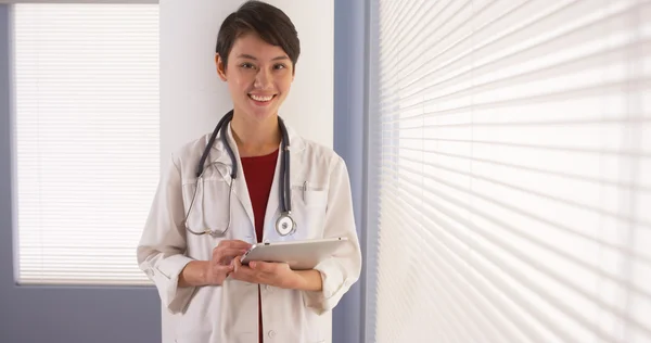 Mulher asiática médico usando tablet por janela — Fotografia de Stock