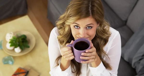Szczęśliwa młoda kobieta picia kawy w salonie — Zdjęcie stockowe