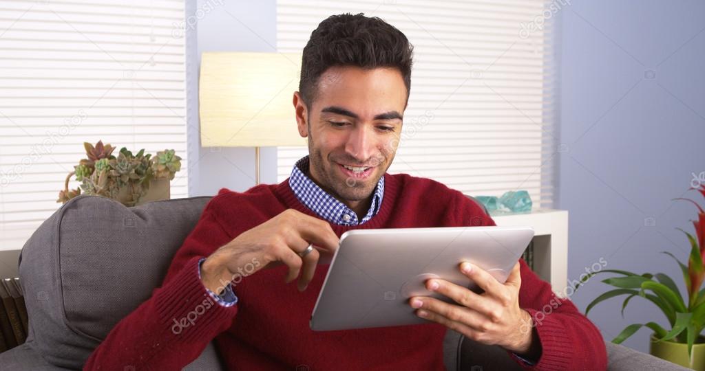 Mexican man using tablet on couch