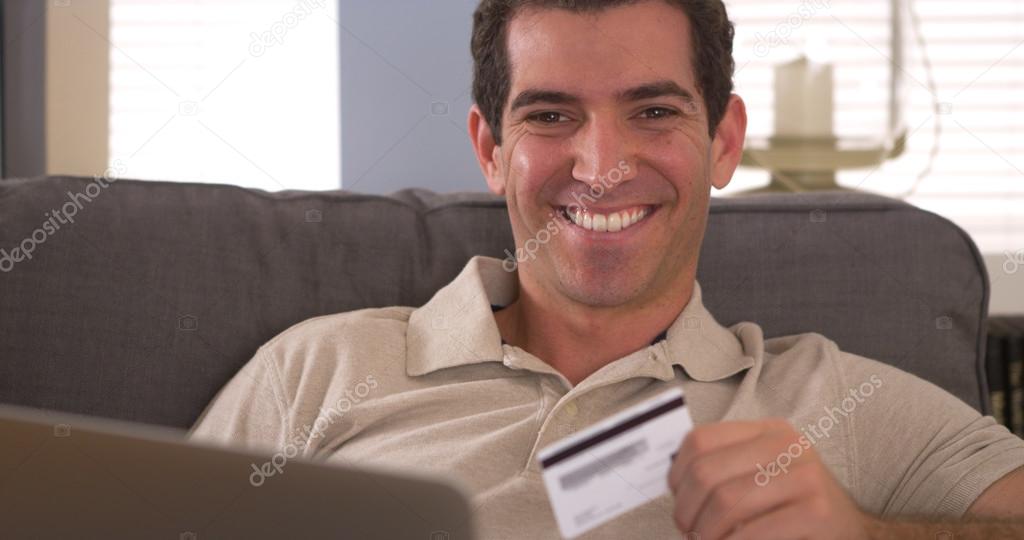 Man smiling with credit card and laptop