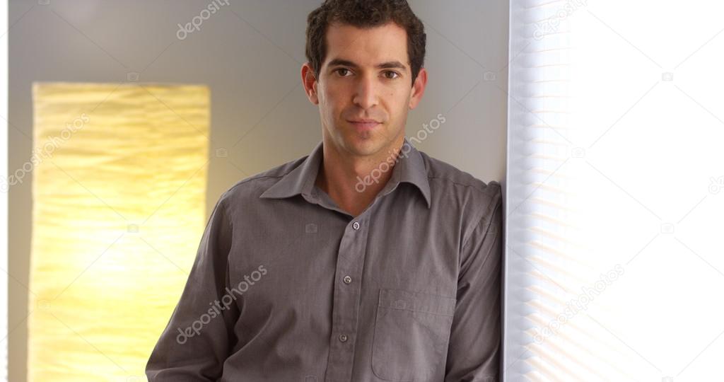 Businessman leaning against wall looking at camera