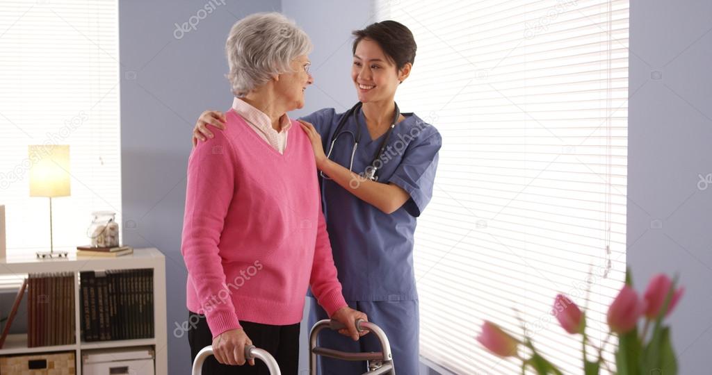Asian nurse and elderly woman patient looking out window