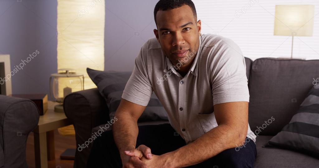 Attractive African bachelor sitting on couch