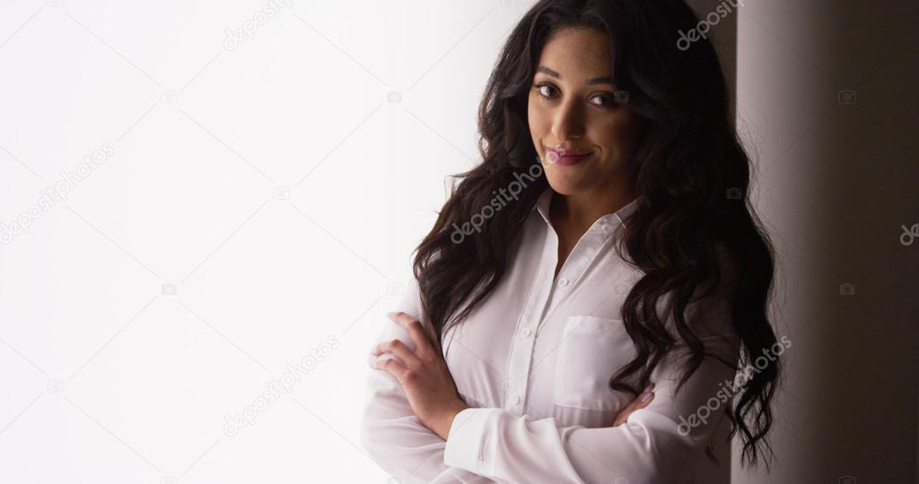 Confident Mexican businesswoman standing by window