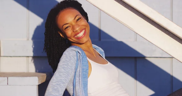 Açık merdivenler gülüyor üzerinde oturan mutlu siyah kadın — Stok fotoğraf