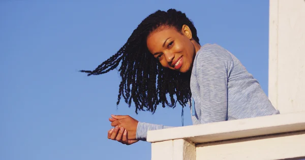 Щаслива чорна жінка, спираючись на рейки посміхаючись — стокове фото
