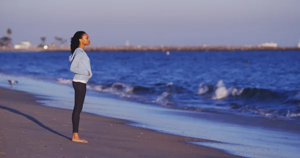Mujer negra disfrutando de la vista al mar hasta que llegan las olas — Foto de Stock