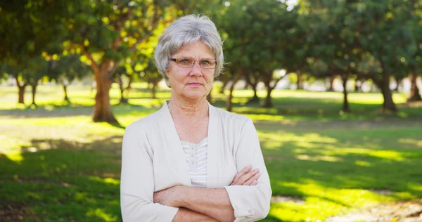 Femme âgée sérieuse debout dans le parc — Photo