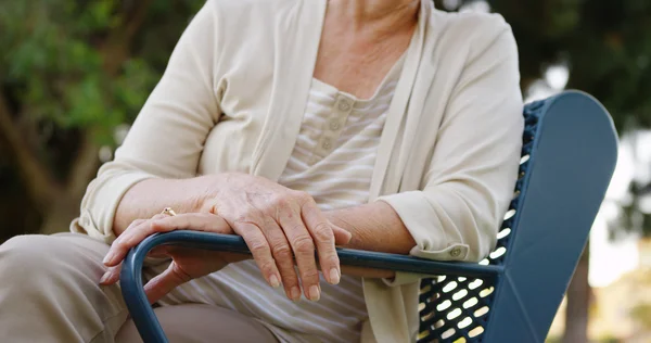 Oudere vrouw zitten op een bankje — Stockfoto