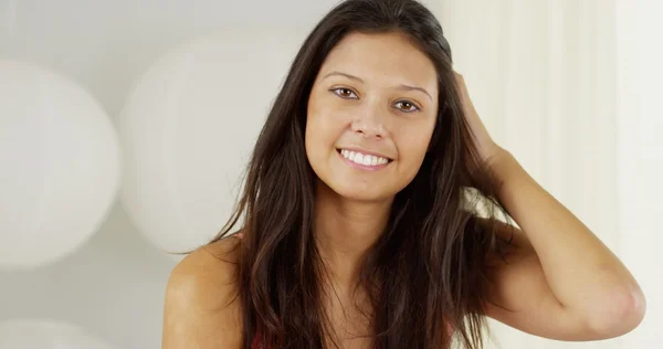 Attraktive hispanische Frau spielt mit Haaren und lächelt in die Kamera — Stockfoto