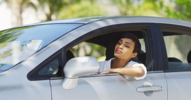 Black woman in car looking around and checking hair in mirror clipart