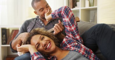 Happy black couple lying on couch with ukulele clipart