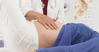 Senior doctor checking pregnant woman's stomach clipart