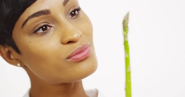 Primer plano de la mujer negra probando espárragos y sonriendo — Foto de Stock