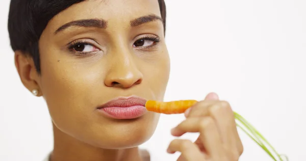 Close up de mulher negra comendo cenoura no fundo branco — Fotografia de Stock
