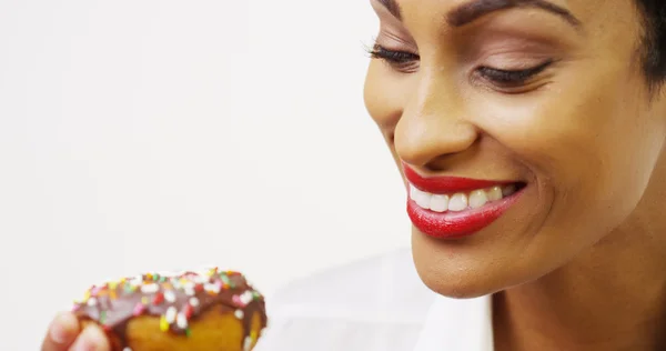 Zwarte vrouw eten chocolade donut met hagelslag en glimlachen — Stockfoto