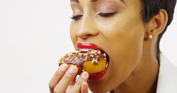 Zwarte vrouw eten chocolade donut met hagelslag en glimlachen — Stockfoto