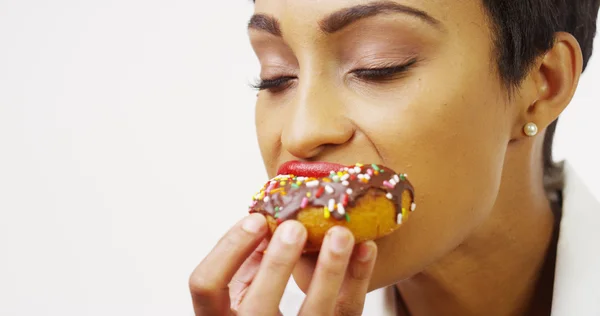 Афроамериканка, балующаяся вкусными шоколадными пончиками с брызгами — стоковое фото